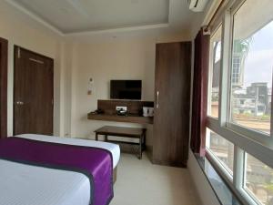 a bedroom with a bed and a tv and a window at Sheldon Inn Kolkata in Kolkata