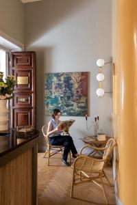 a woman sitting in a chair reading a book in a room at Glance in Rome in Rome +70 photos