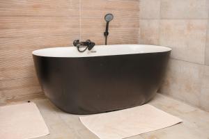 a black bath tub in a bathroom with two rugs at Harnham Mountain Lodge in Louis Trichardt