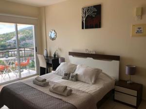 1 dormitorio con 1 cama y balcón con mesa en Panoramic Holidays - Superior 41, en Peyia