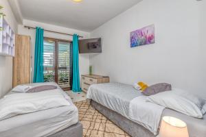 two beds in a bedroom with blue curtains at Wellness Apartment in Poreč