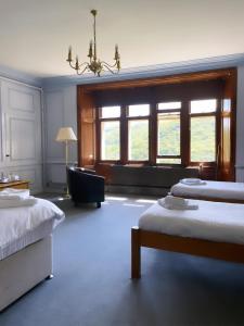 a bedroom with two beds and a chair and a window at Plas Tan y Bwlch in Maentwrog