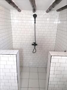 Una ducha de azulejos blancos con una sombrilla negra. en New Arisen Bungalows en Bwejuu