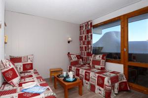 a living room with red and white chairs and a window at Résidence Odalys Le Hameau du Mottaret in Méribel