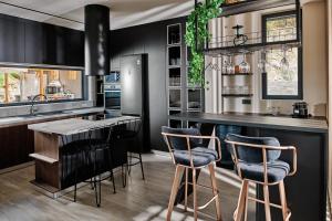 una cocina con armarios negros y una barra con taburetes en Althea Lavish Estate - Villa & Suite en Zakynthos