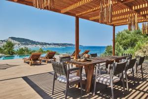 una mesa de madera y sillas en una terraza con vistas al océano en Althea Lavish Estate - Villa & Suite en Zakynthos