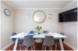 een eetkamer met een witte tafel met stoelen en een spiegel bij Wells City Centre, Quiet Mews House, sleeps 6 in Wells