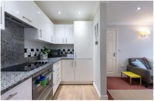 a kitchen with white cabinets and a couch at Wells City Centre, Quiet Mews House, sleeps 6 in Wells