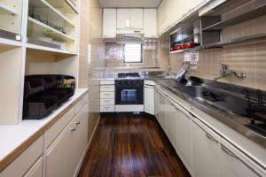 a kitchen with white cabinets and a wooden floor at G’Day Senbayashi in Osaka