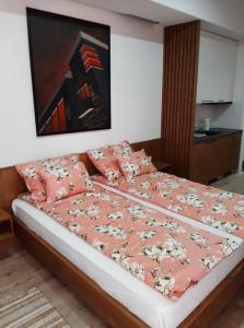 um quarto com uma cama com lençóis e almofadas cor-de-rosa em Apartment Mašić em Sombor