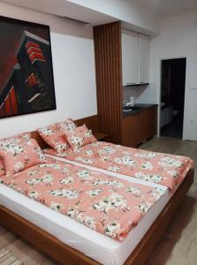 a bedroom with a bed with pink sheets and pillows at Apartment Mašić in Sombor