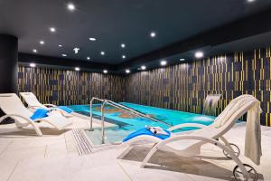 a swimming pool with white chairs and a swimming pool at Hotel Ferreus Modern Art Deco in Krakow