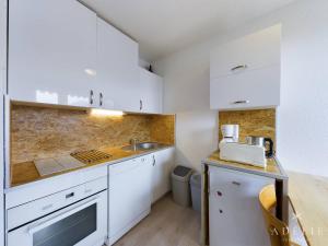 a small kitchen with white cabinets and a sink at Studio rénové skis aux pieds, balcon sud, parking inclus, proche commerces et garderie. - FR-1-398-512 in La Rosière