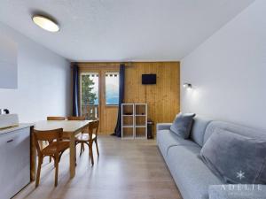 a living room with a couch and a table at Studio rénové skis aux pieds, balcon sud, parking inclus, proche commerces et garderie. - FR-1-398-512 in La Rosière