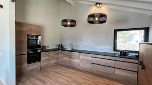 a kitchen with wooden cabinets and two pendant lights at Watervilla it Beaken in Heeg