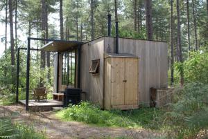 eine Holzhütte im Wald mit einem Herd in der Unterkunft Recreation Park Warredal in Neeroeteren