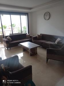 a living room with couches and a clock on the wall at Prestigia in Sidi Bouqnadel
