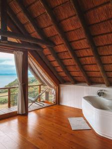a bathroom with a tub and a large window at Dreamland Beach House & Studios at Supertubes in Jeffreys Bay