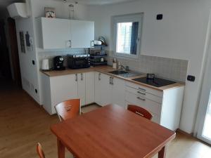 a kitchen with white cabinets and a wooden table at La Gabbianella - Locazione turistica in Marone