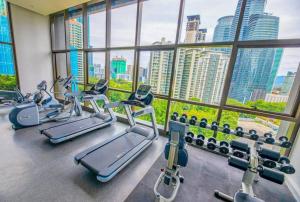 a gym with cardio machines in front of a large window at 8 Kia Peng Residences by StayHere in Kuala Lumpur
