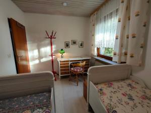 1 dormitorio con 2 camas, escritorio y ventana en Ferienwohnung Gutermuth Obereisenheim, en Fahr