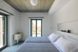 a white bedroom with a large bed and a window at Kymo Kea in Otziás