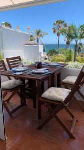 una mesa de madera y sillas en un patio con vistas al océano en Espectacular apartamento primera linea de playa - Golf en Estepona