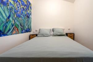 a bed in a room with a painting on the wall at Appartement à L'Isle-sur-la-Sorgue avec vue sur la ville in LʼIsle-sur-la-Sorgue