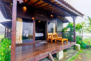 a wooden porch with two chairs and a bed at The Joglo Beratan in Bedugul