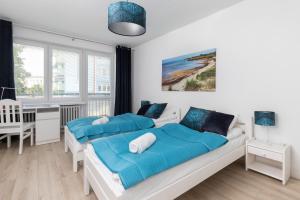 two beds in a white bedroom with a desk and window at Gdańska Two-bedroom Apartment Brzeźno Beach by Renters in Gdańsk