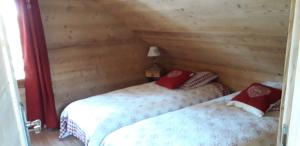 two beds in a room with wooden walls at Chalet cocody jacuzz in Jausiers