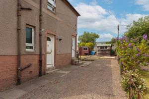 a brick building with a white door and a sidewalk at Lovely 2-bed upper villa in Kirkliston Edi Airport in Edinburgh