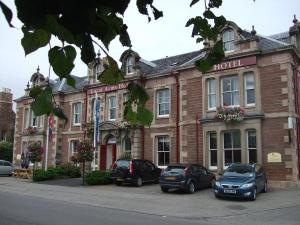 a hotel with three cars parked in front of it at Lovat Arms Hotel in Beauly