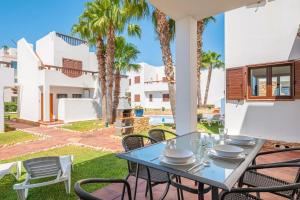 a patio with a table and chairs and palm trees at LA PERLA DE CALA DOR in Portopetro