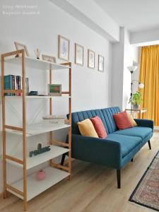 a living room with a blue couch and a book shelf at Cozy Apartment Bujorilor Suceava in Suceava