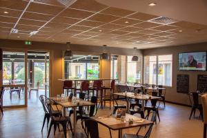 a dining room with tables and chairs and windows at Campanile Dunkerque Sud - Loon Plage in Loon-Plage