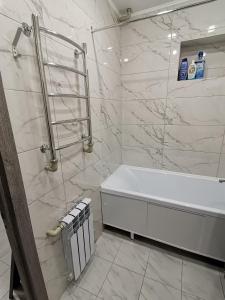 biała łazienka z wanną i prysznicem w obiekcie Чистая уютная квартира! Рядом сквер,море w mieście Aktau