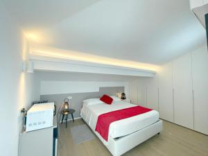 una camera con un letto bianco e una coperta rossa di La Mansardina a Riccione