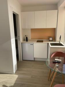 kuchnia z białymi szafkami i szklanym stołem w obiekcie Torremolinos,estudio junto al mar en La Carihuela w mieście Torremolinos