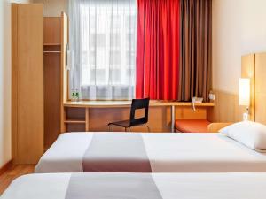 ワルシャワにあるイビス ワルシャワ レドゥータのベッド2台とデスクが備わるホテルルームです。