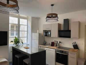 a kitchen with white cabinets and a black counter top at La roue des teinturiers in Avignon