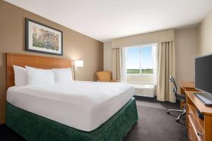 a large white bed in a hotel room with a window at Baymont by Wyndham Fremont in Fremont