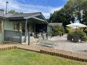 a patio with chairs and an umbrella next to a house at Kingfisher Lodge, South View Lodges, Exeter in Exeter