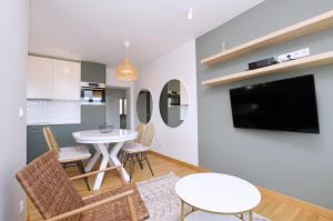 ein Wohnzimmer mit einem Tisch und Stühlen sowie einem TV in der Unterkunft Victus Apartamenty, Apartament Boho in Sopot