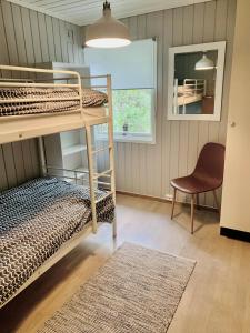 um quarto com 2 beliches e uma cadeira em Renovated sea facing cottage on the Eidanger fjord em Porsgrunn