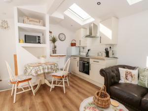 a kitchen and living room with a couch and a table at Primrose Cottage in Mold