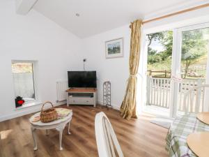 a living room with a television and a table at Primrose Cottage in Mold