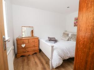 um quarto com uma cama e uma cómoda com um espelho em Primrose Cottage em Mold