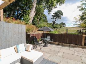 a patio with a white couch and an umbrella at Primrose Cottage in Mold