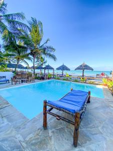 a pool at a resort with palm trees and the ocean at Villa Thamani Zanzibar in Pwani Mchangani